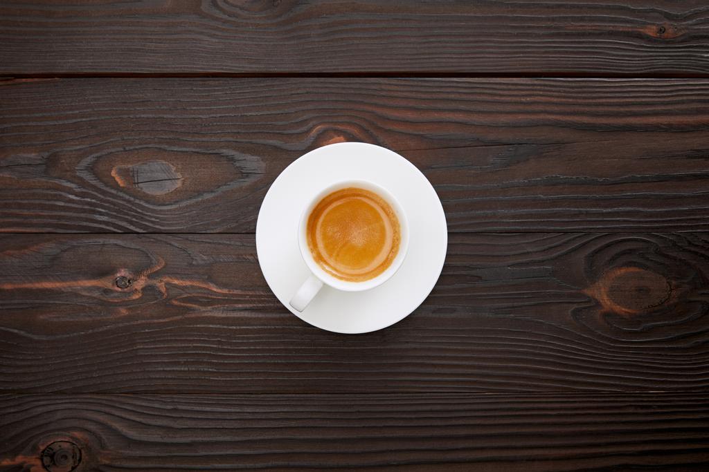 вид зверху чашки кави з тарілкою на дерев'яній поверхні
 - Фото, зображення