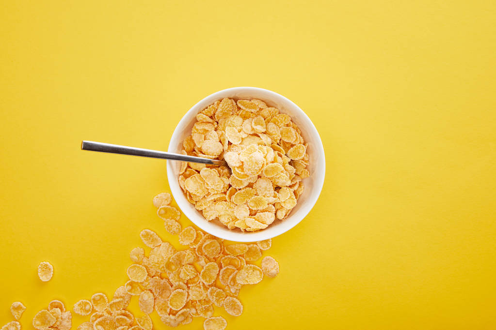 top view of bowl with cornflakes near scattered pieces isolated on yellow - Photo, Image