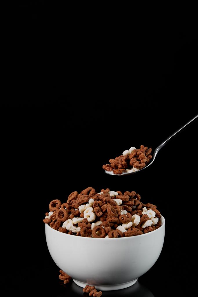 ciotola bianca con cereali assortiti e cucchiaio isolato su nero
 - Foto, immagini