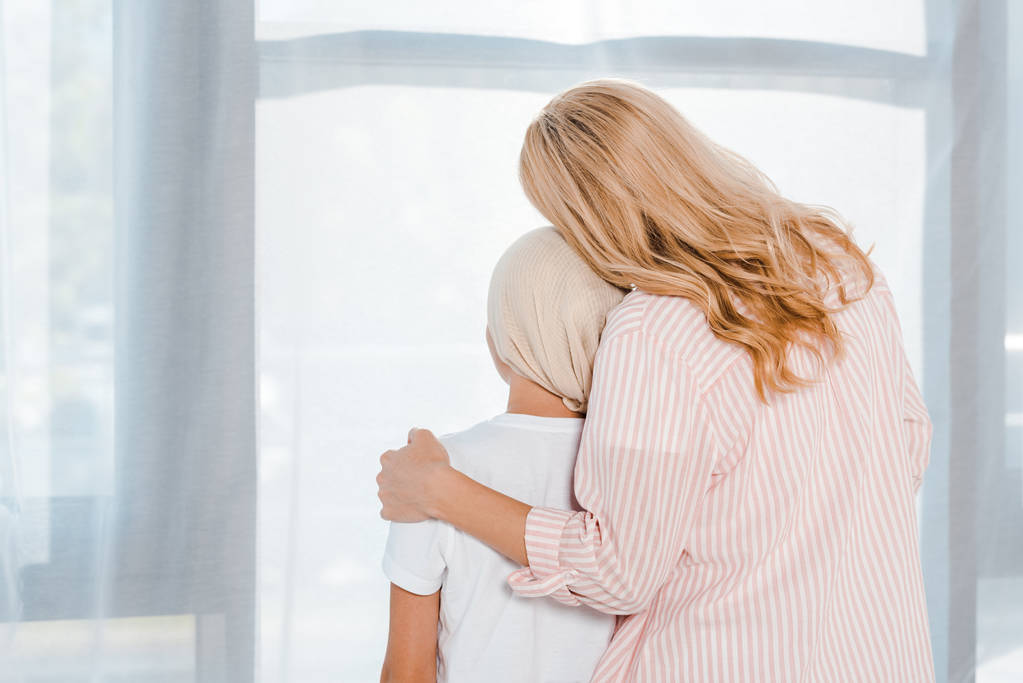 indietro vista di madre abbracciando figlia in testa sciarpa
  - Foto, immagini