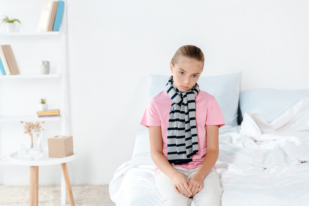 niño enfermo en bufanda sentado en la cama en casa
  - Foto, Imagen