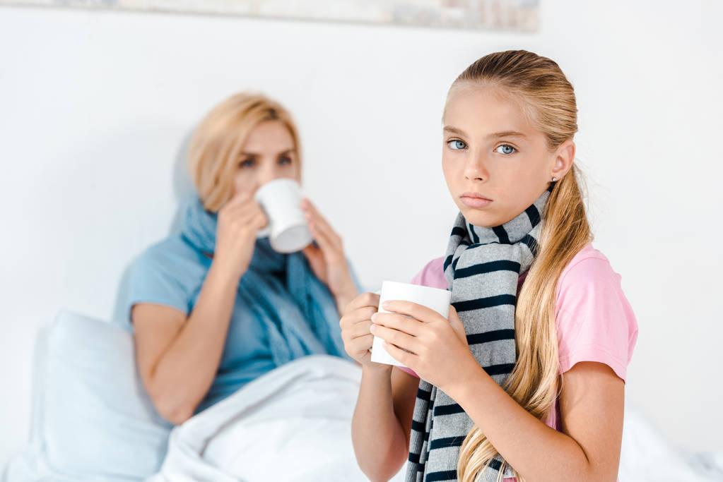 selective focus of sick kid holding cup near mother  - Photo, Image