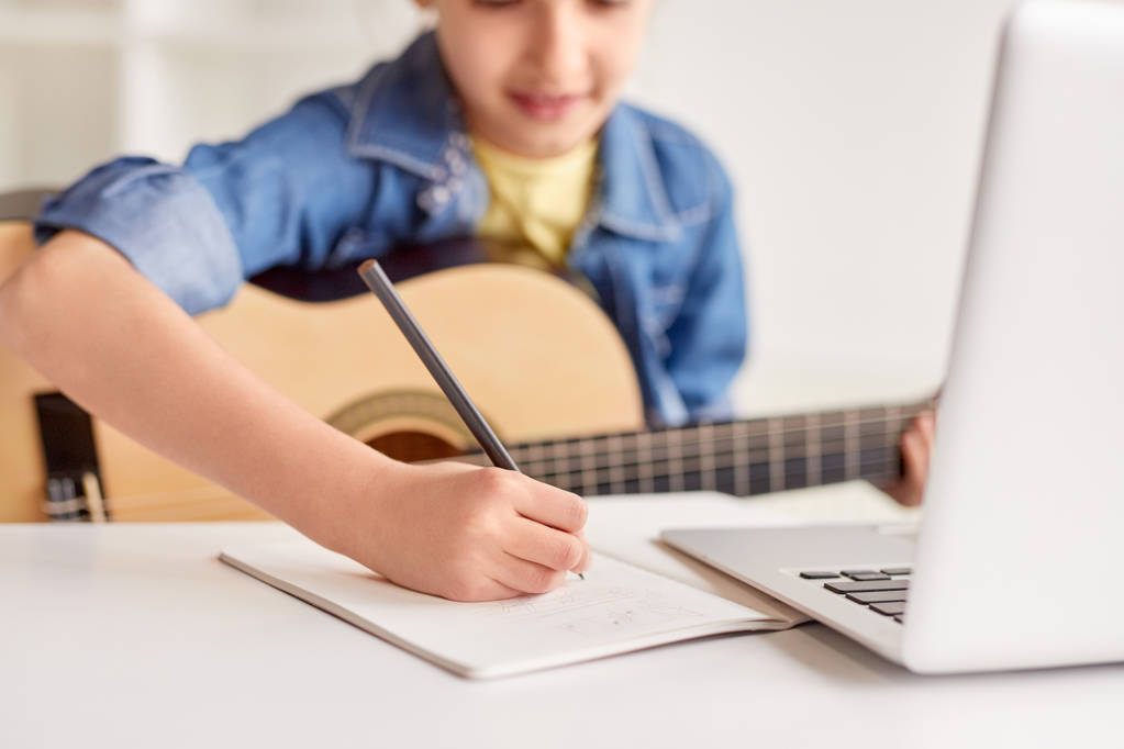 Meisje maken van notities tijdens gitaar les - Foto, afbeelding