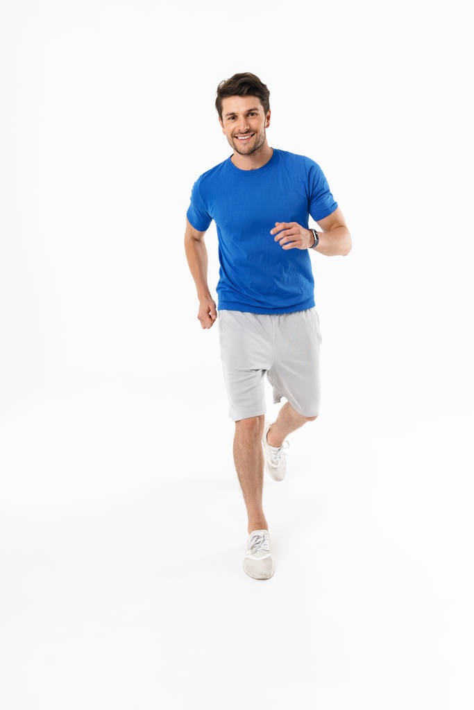 Foto eines fröhlichen, athletischen Mannes in kurzen Hosen und T-Shirt, der lächelt, während - Foto, Bild