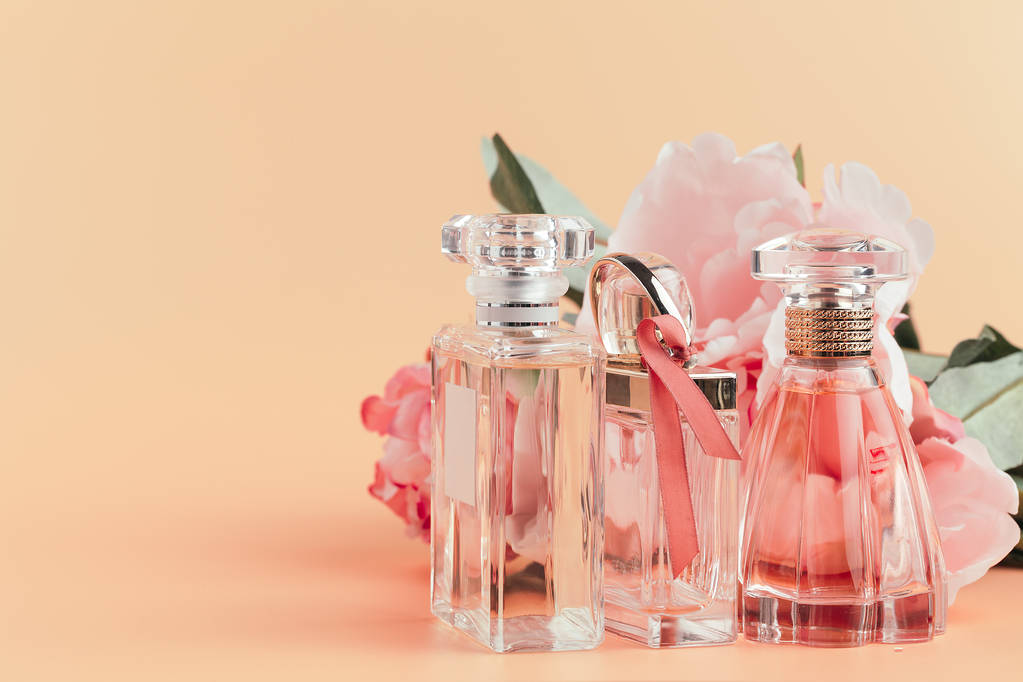 Hafif kumaş üzerinde çiçekler olan bir şişe parfüm. - Fotoğraf, Görsel