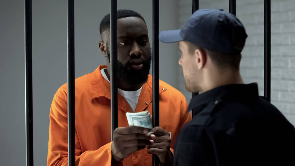 Αφρικανός Αμερικανός κρατούμενος που δίνει δολάρια μετρητά για φρουρά, διαφθορά στη φυλακή, δωροδοκία - Φωτογραφία, εικόνα