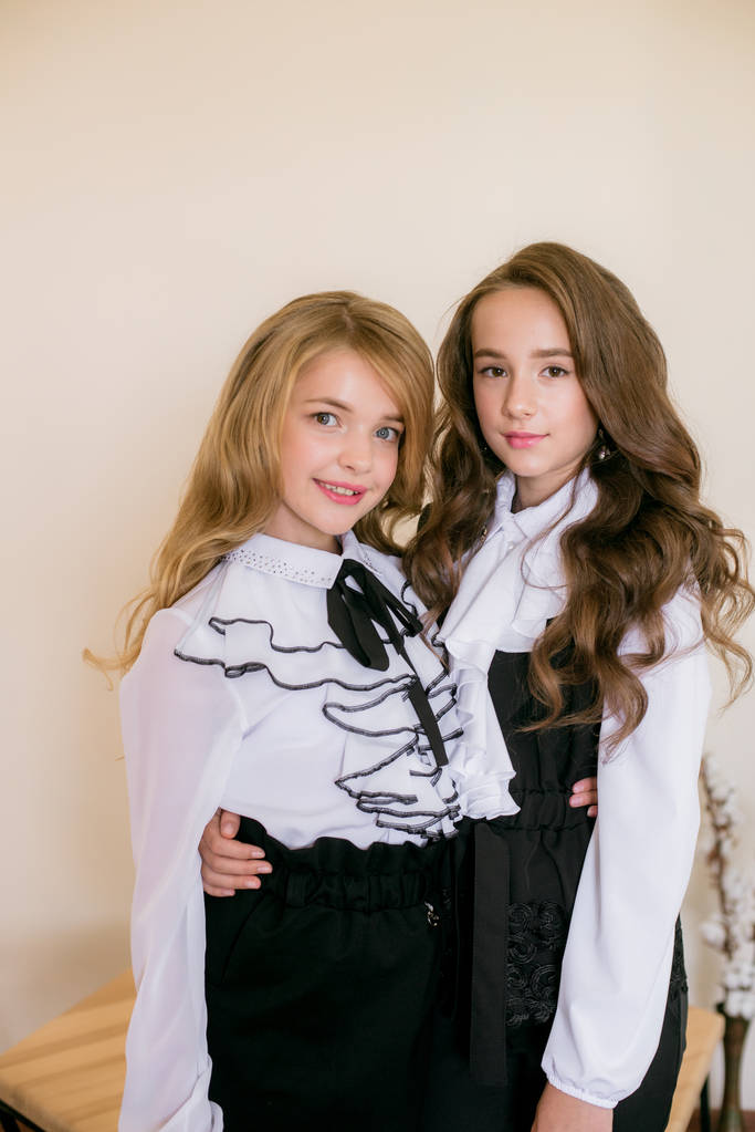 Dvě milé dívky s dlouhými kudrnatými vlasy v módních školních šatech. Školní móda ve vinobraní stylu. - Fotografie, Obrázek