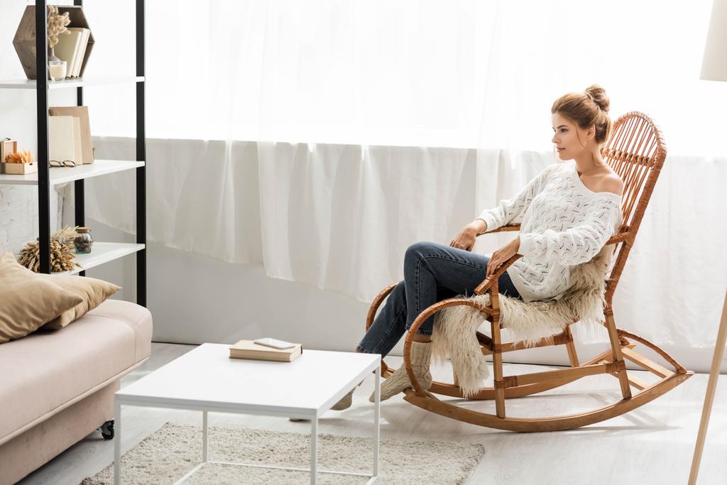 привлекательная женщина в белом свитере сидит на кресле-качалке
 - Фото, изображение