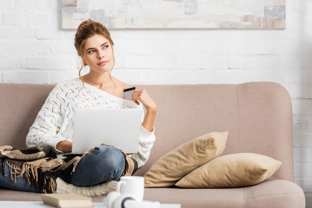 mulher atraente em suéter branco segurando crédito e laptop
 - Foto, Imagem