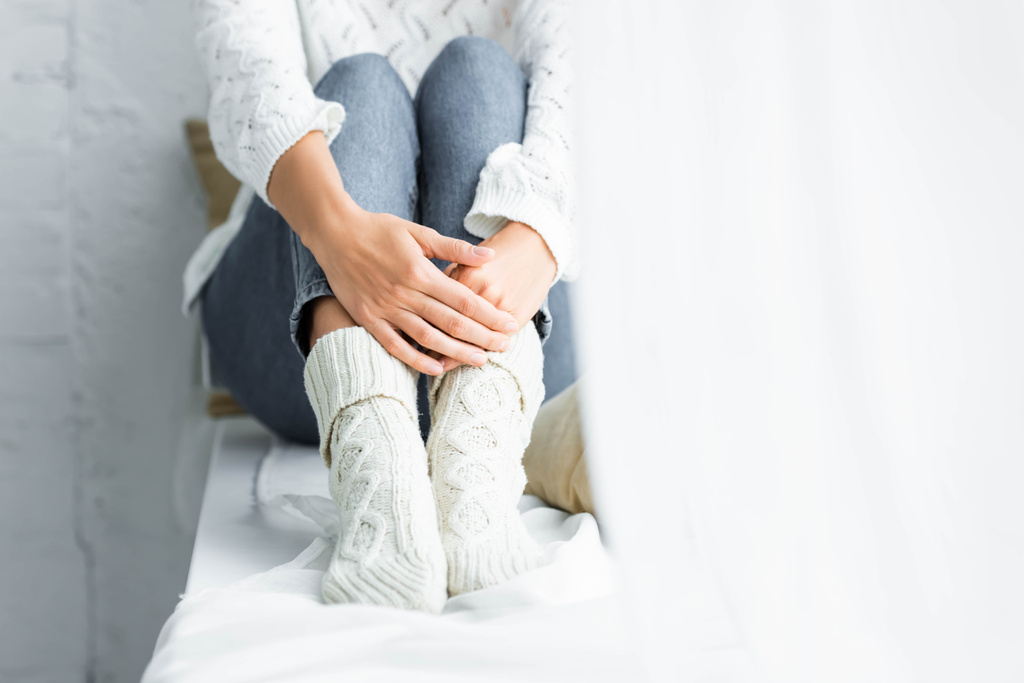 vista recortada de la mujer en suéter blanco y jeans sentados en el apartamento
  - Foto, Imagen