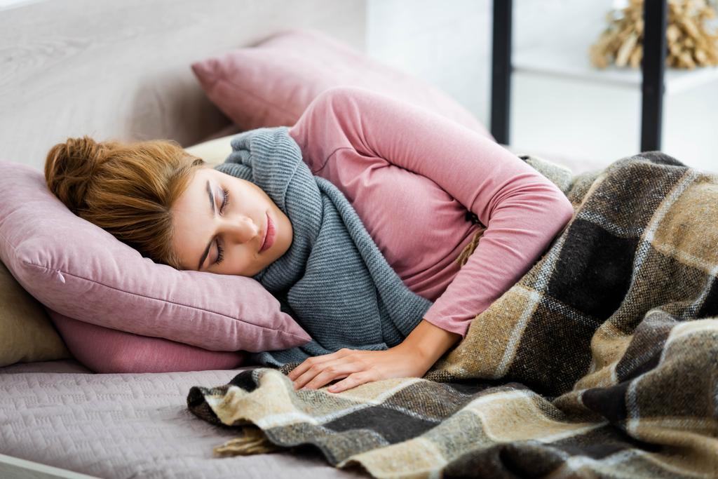 ελκυστική και άρρωστη γυναίκα με γκρι κασκόλ ύπνου στο κρεβάτι  - Φωτογραφία, εικόνα