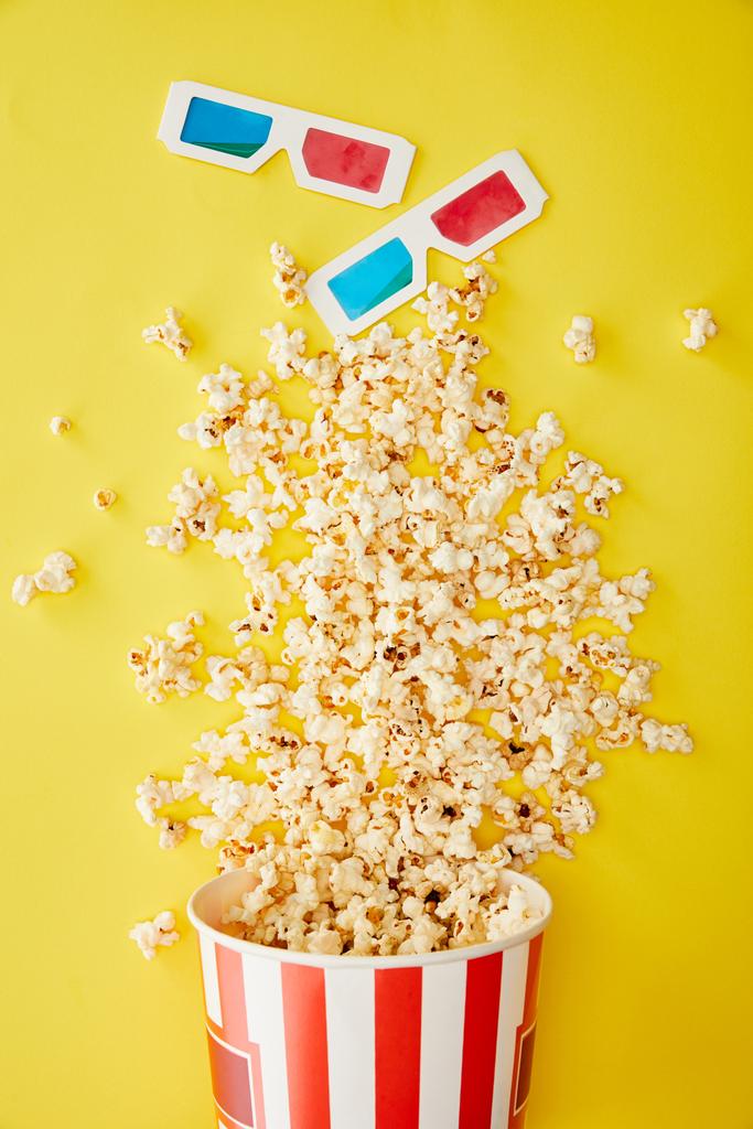 top view of delicious popcorn scattered near 3d glasses on yellow background - Photo, Image