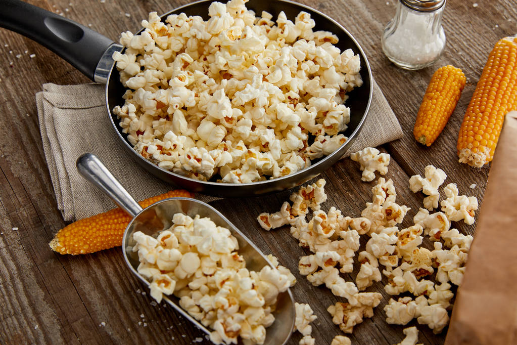 delicious popcorn in frying pan and on wooden table - Photo, Image