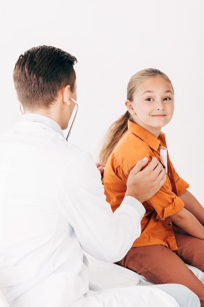pediatrist in white coat examining kid with stethoscope isolated on white - Photo, Image