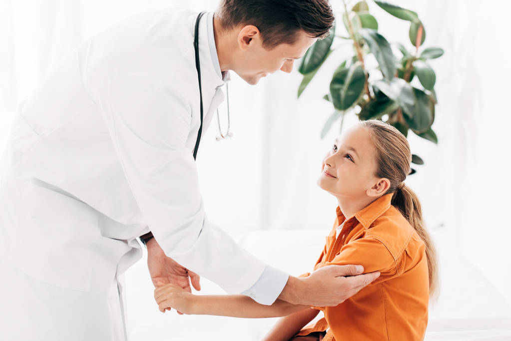 pediatra de bata blanca examinando a un niño en la clínica
 - Foto, imagen