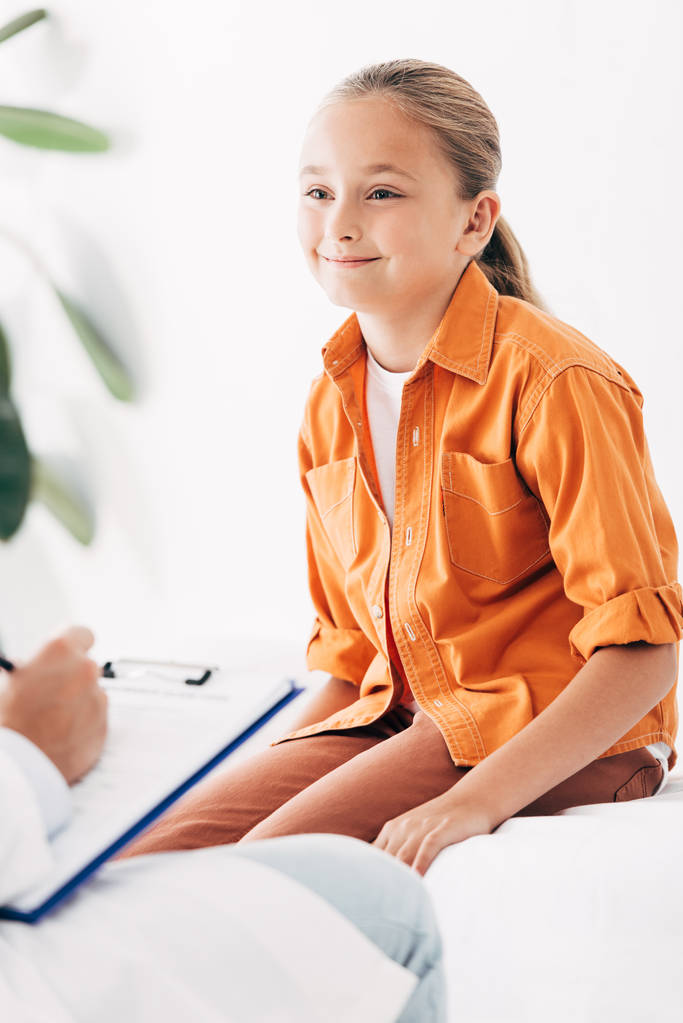 μερική προβολή της pediatrist γραφής στο πρόχειρο κατά την εξέταση παιδιού στην κλινική - Φωτογραφία, εικόνα