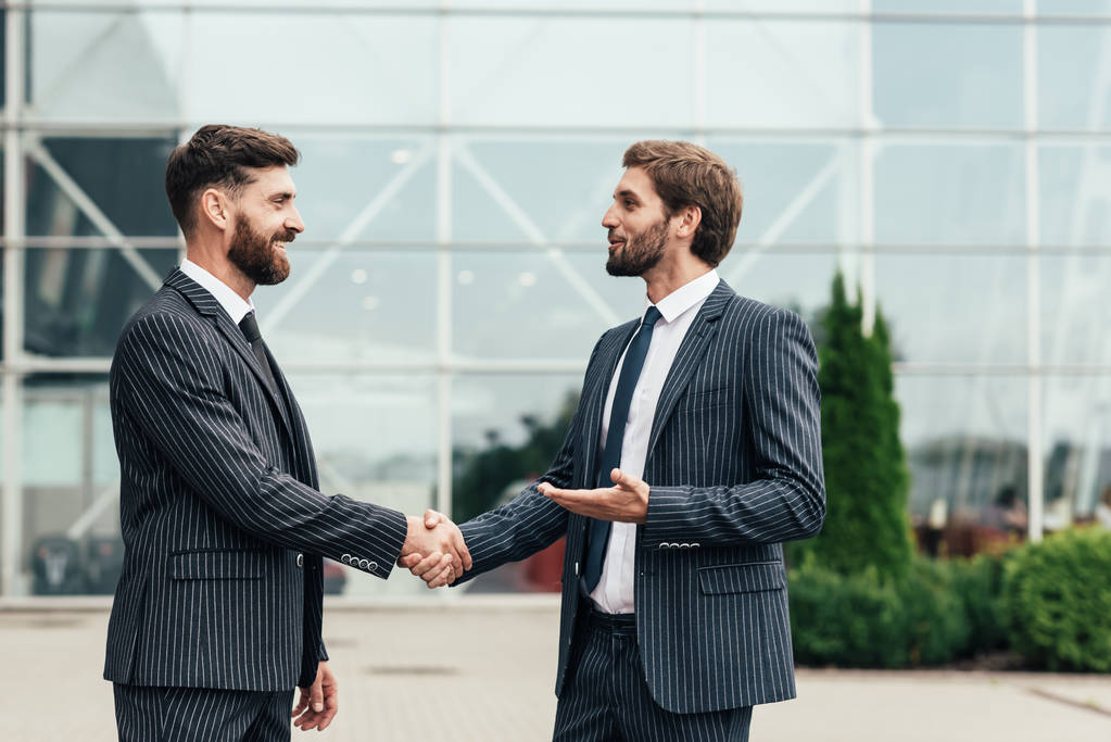 Представьте двух бизнес-партнеров в элегантном костюме, которые успешно пожимают друг другу руки.
 - Фото, изображение