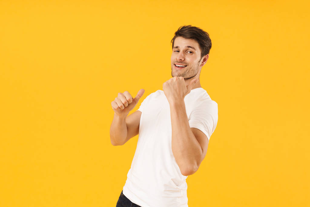 Foto van positieve man in Basic t-shirt glimlachend en gebaren fin - Foto, afbeelding