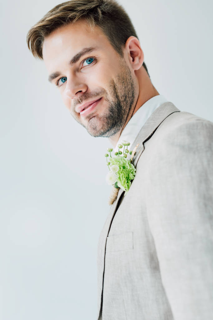 novio guapo en traje con boutonniere floral mirando cámara aislada en gris
 - Foto, imagen