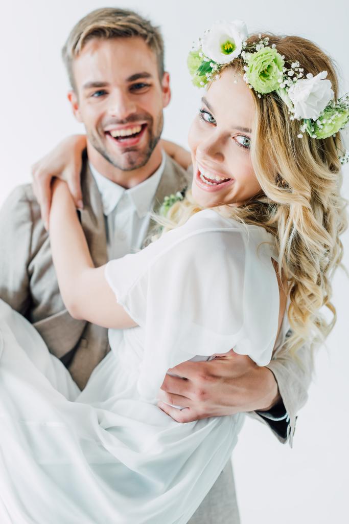 attraktive Braut und schöner Bräutigam umarmen sich und schauen in die Kamera - Foto, Bild