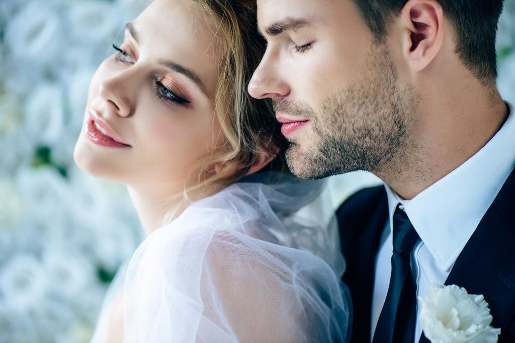 attraktive Braut und schöner Bräutigam im Anzug mit geschlossenen Augen  - Foto, Bild