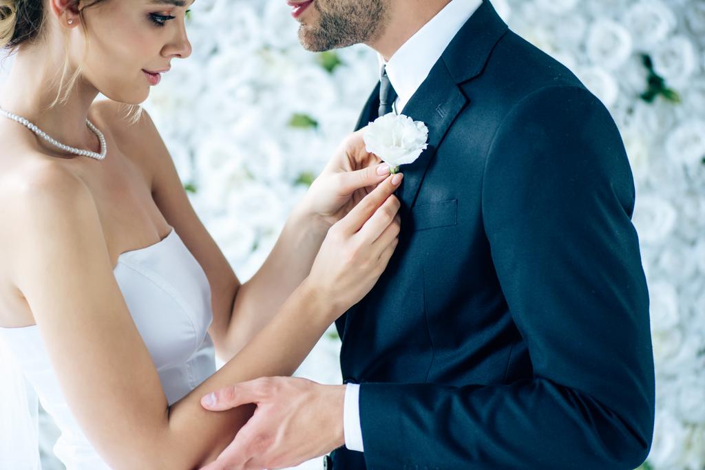 vista cortada da noiva em vestido de noiva segurando botão de seu noivo
  - Foto, Imagem
