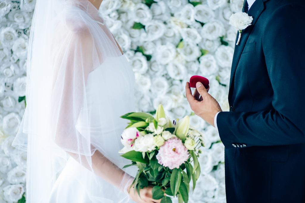 вид збоку нареченого, що пропонує нареченій у весільній сукні
  - Фото, зображення
