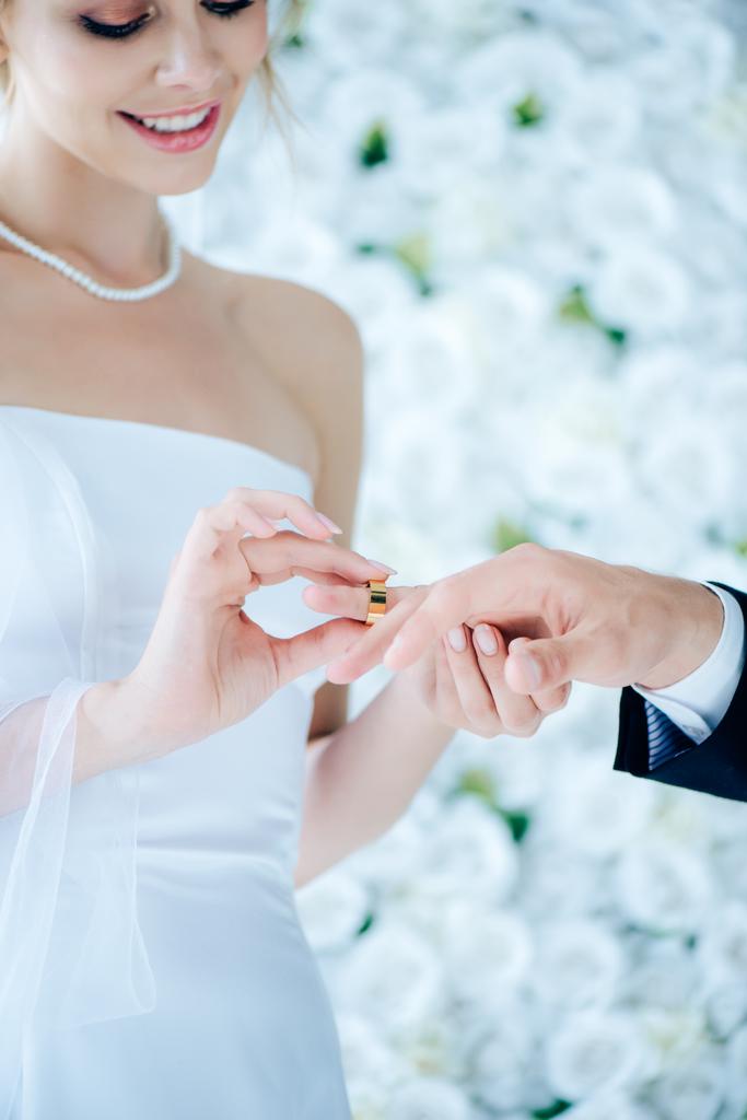 atractiva y sonriente novia poniendo anillo de bodas en el dedo
  - Foto, imagen