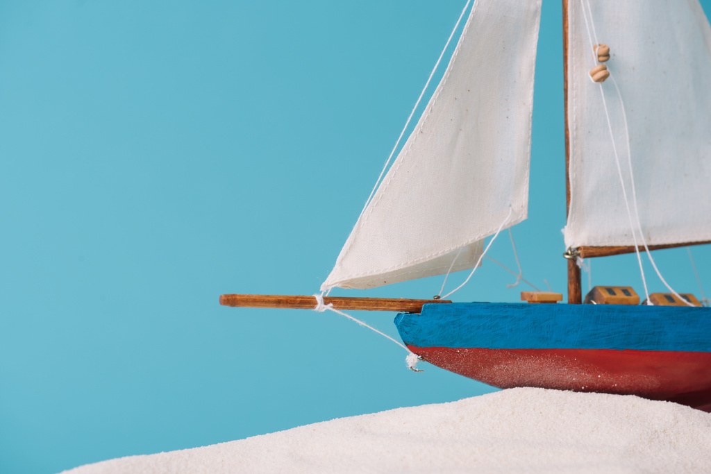 Close-up weergave van decoratief schip in wit zand geïsoleerd op blauw - Foto, afbeelding