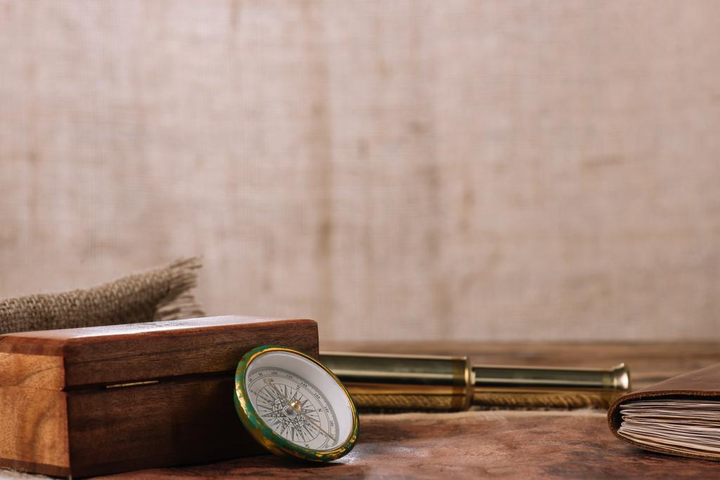 hnědá Dřevěná bedna v blízkosti kompasu a zlatého dalekohledu a kusu saku - Fotografie, Obrázek