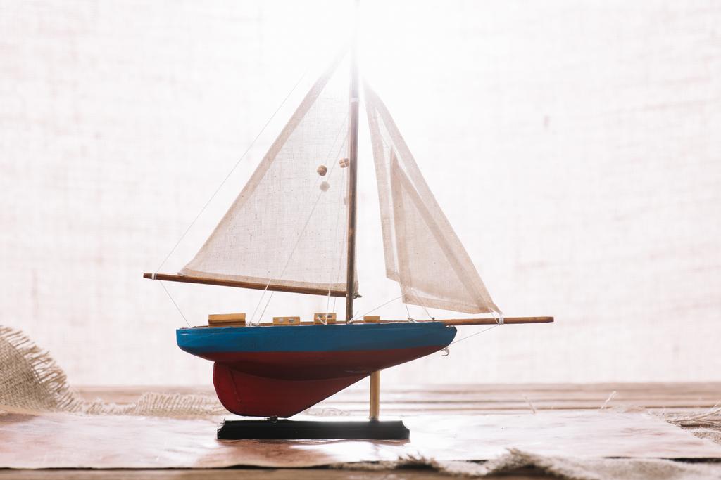 barco decorativo con vela blanca en la superficie con hessian
 - Foto, Imagen