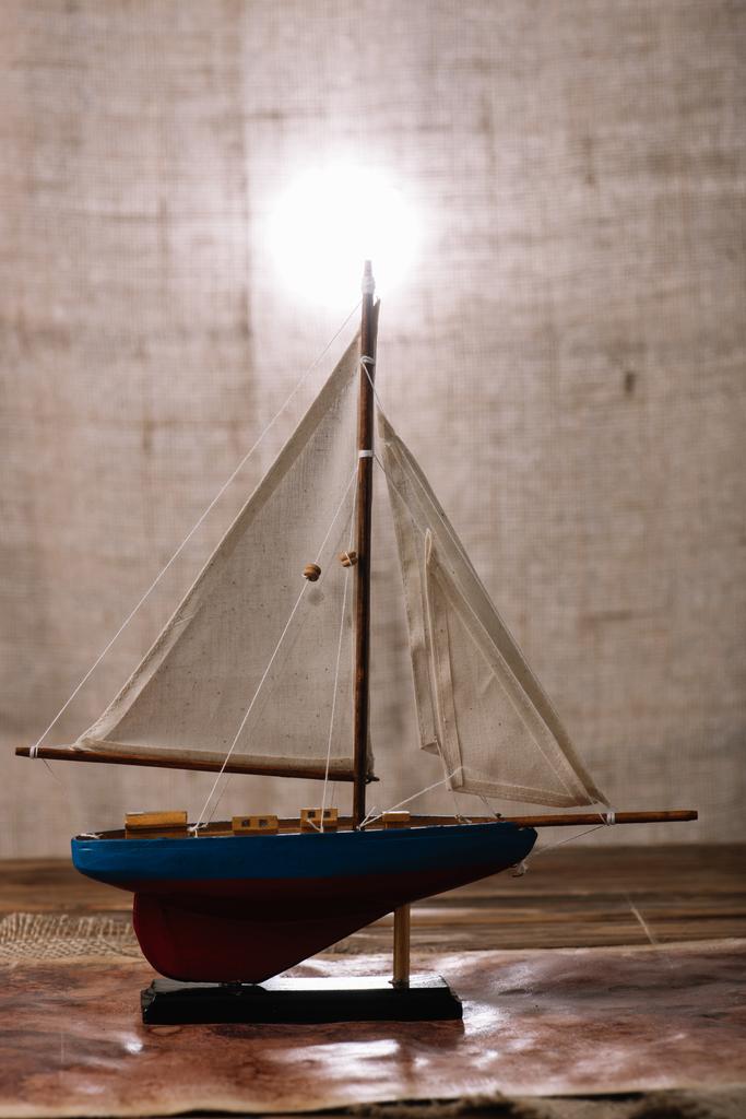 木製の表面に白い帆が付いている装飾的な船 - 写真・画像