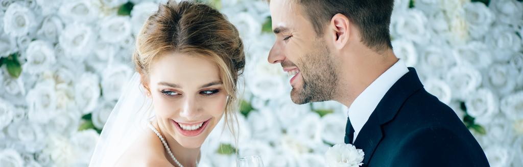 plan panoramique de la mariée attrayante et beau marié souriant avec les yeux fermés
  - Photo, image