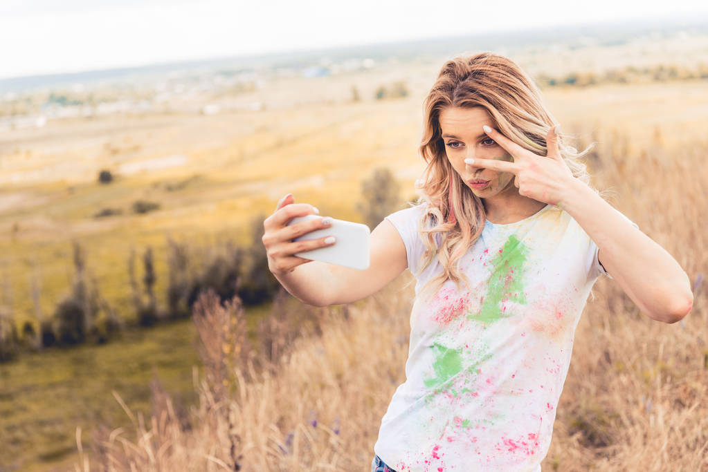 attraktive Frau im T-Shirt macht Selfie und zeigt Friedenszeichen  - Foto, Bild