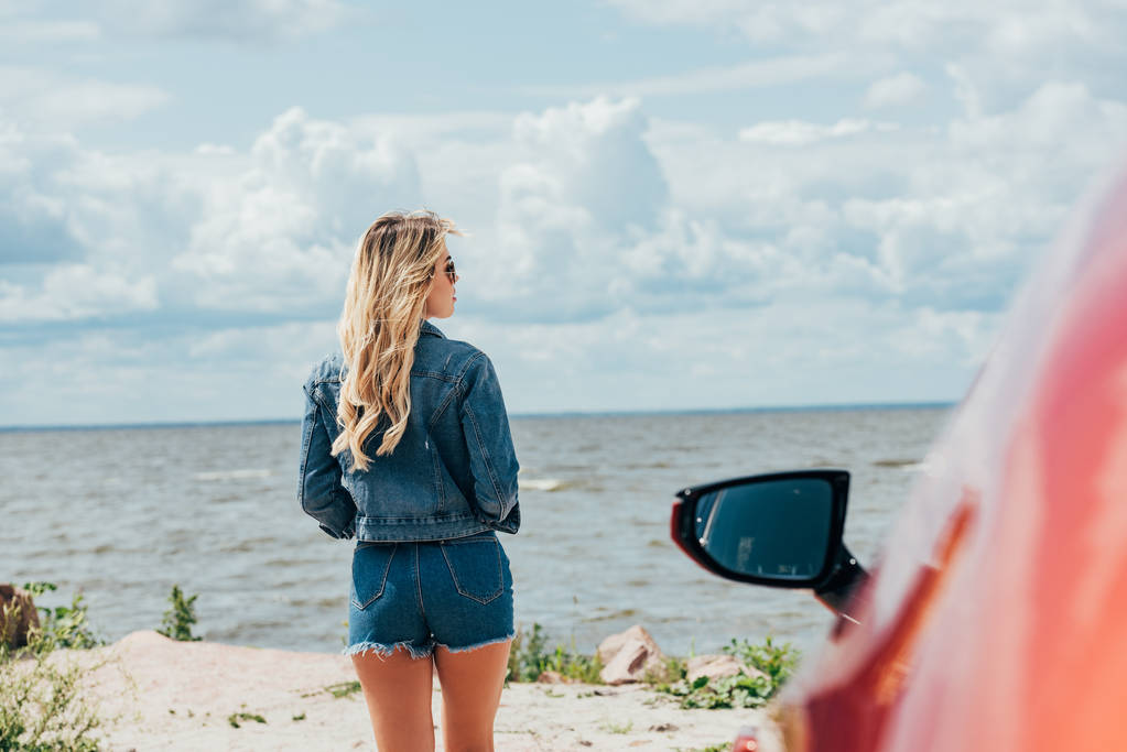 back view of woman in denim jacket and shorts looking away  - Photo, Image
