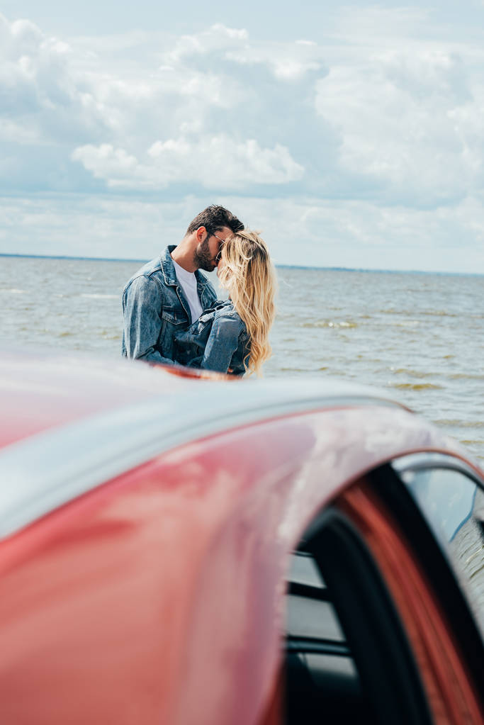 selective focus of woman and man in denim jackets kissing outside  - Photo, Image