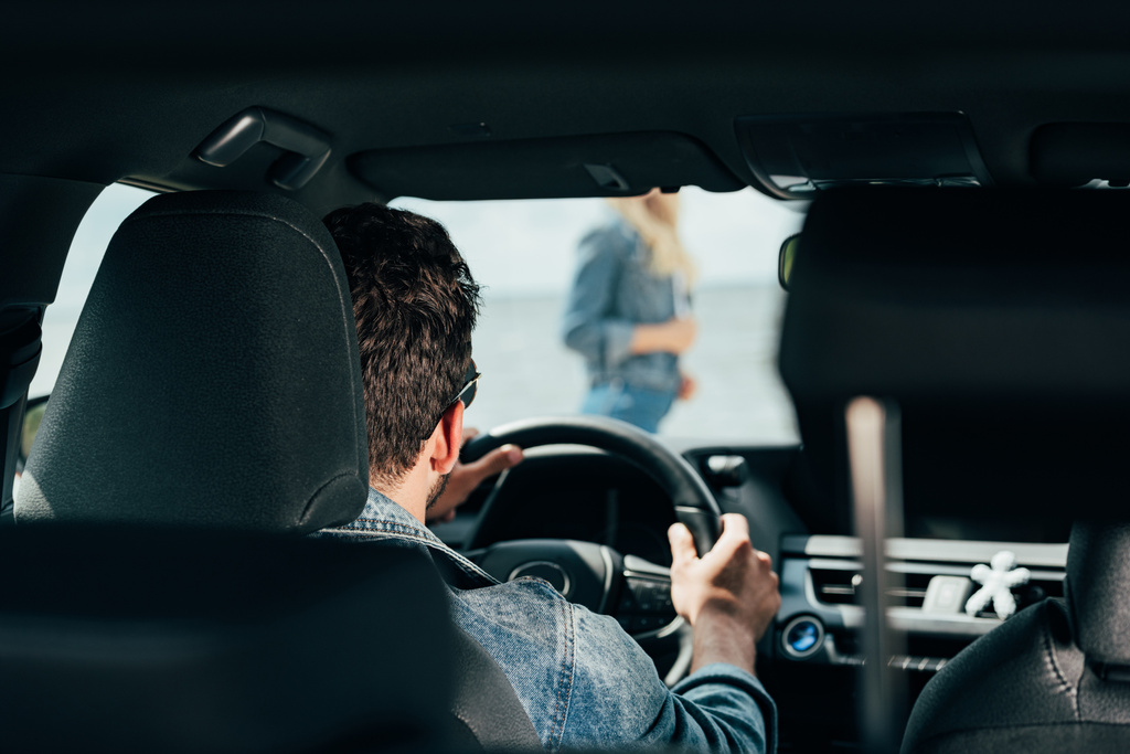 Вид сзади мужчины, сидящего в машине и смотрящего на женщину
  - Фото, изображение
