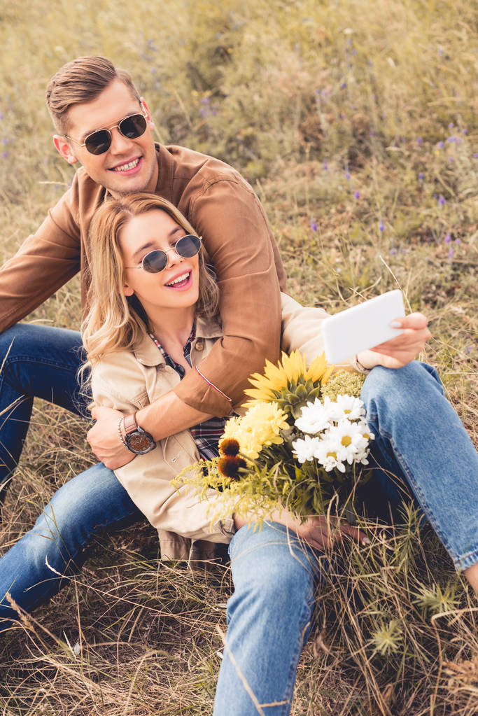 houkutteleva nainen kukkakimppu ja komea mies ottaen selfie
  - Valokuva, kuva