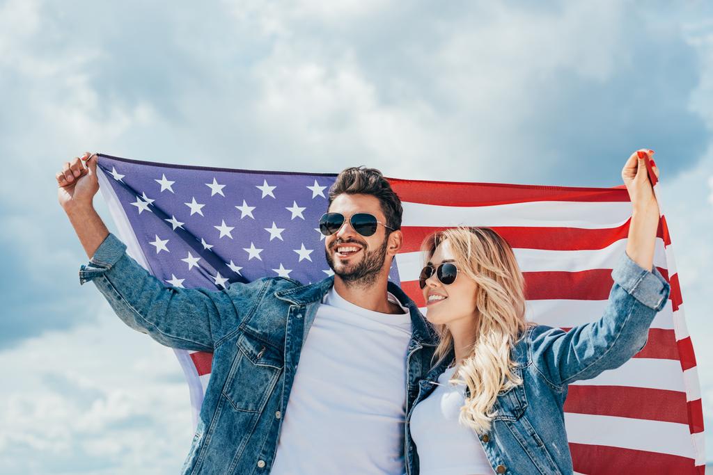 ελκυστική γυναίκα και όμορφος άντρας χαμογελώντας και κρατώντας αμερικάνικη σημαία  - Φωτογραφία, εικόνα