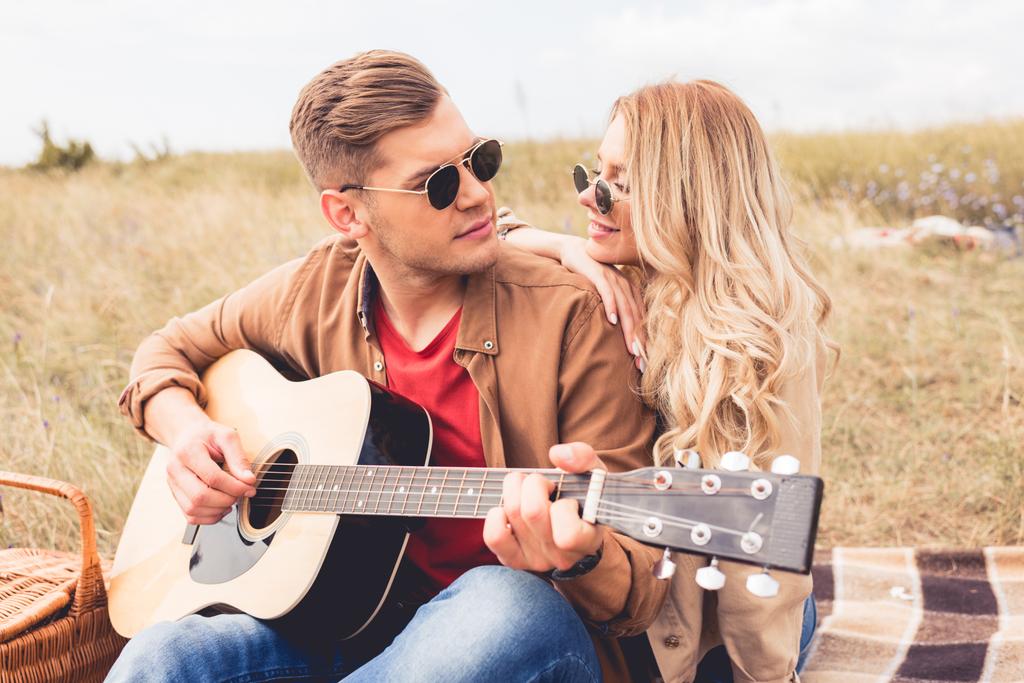 guapo hombre tocando la guitarra acústica y atractiva mujer abrazándolo
  - Foto, Imagen