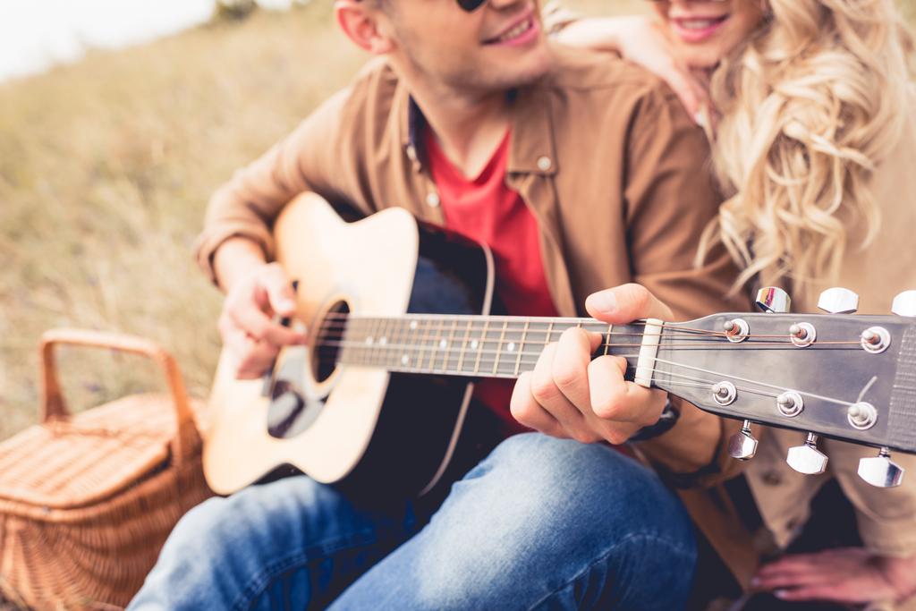 アコースティックギターを弾く男性と彼を抱きしめる女性の選択的な焦点  - 写真・画像