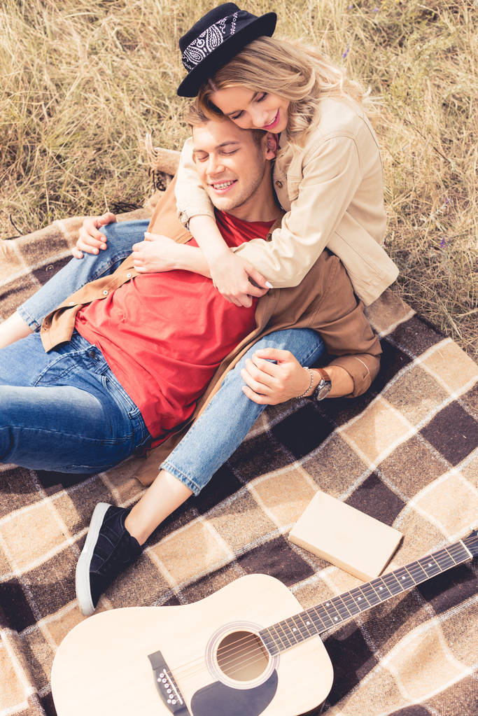θέα της υψηλής γωνίας του όμορφου άντρα και της γυναίκας που αγκαλιάζονται και κάθονται στην κουβέρτα  - Φωτογραφία, εικόνα