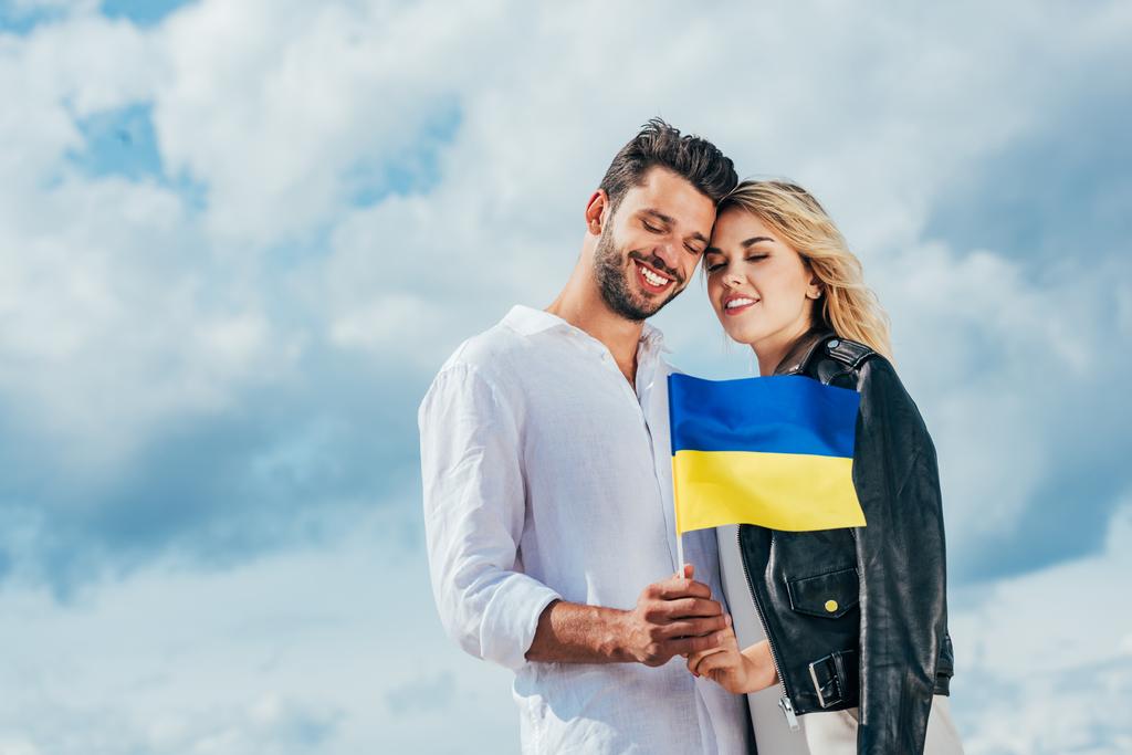 attractive woman and handsome man holding ukrainian flag outside  - Photo, Image