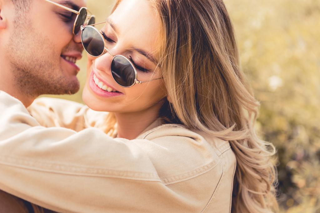 привлекательная женщина обнимается и целуется с красивым мужчиной в солнечных очках
 - Фото, изображение