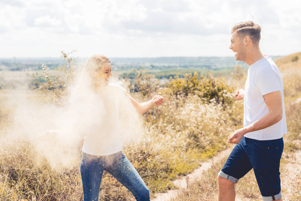 attractive woman and handsome man in t-shirts throwing colorful powder - Photo, Image