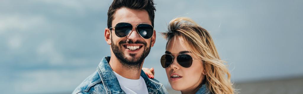 panoramic shot of attractive woman and handsome man in sunglasses smiling outside  - Photo, Image