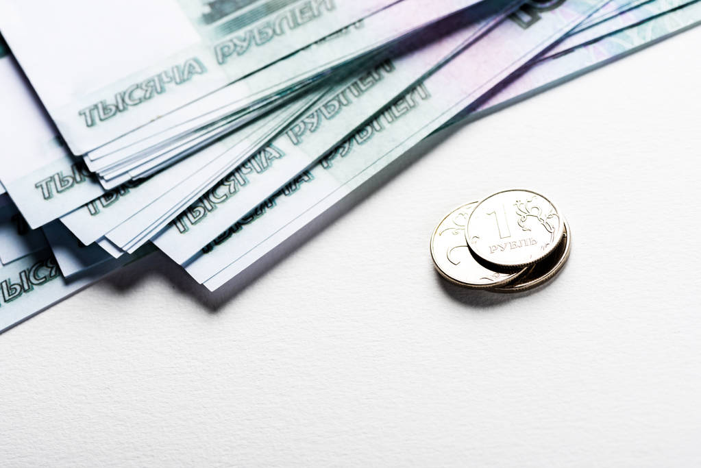 серебряные монеты рядом с российскими деньгами, изолированными на белом
  - Фото, изображение