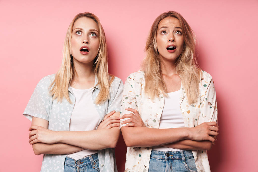 Emotioneel geschokt pretty Blondes vrouwen vrienden poseren geïsoleerd over roze muur achtergrond. - Foto, afbeelding