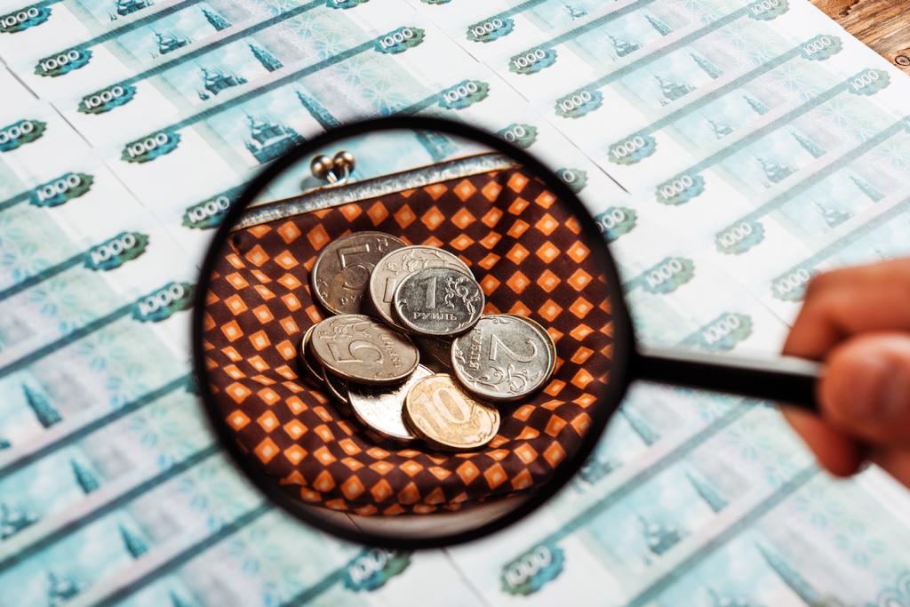 селективний фокус людини тримає лупа біля монет у картаті гаманець біля російських грошей  - Фото, зображення
