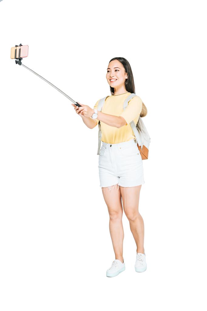 beyaz arka planda selfie çubuğu ile akıllı telefonda selfie çeken çekici asyalı kadın - Fotoğraf, Görsel